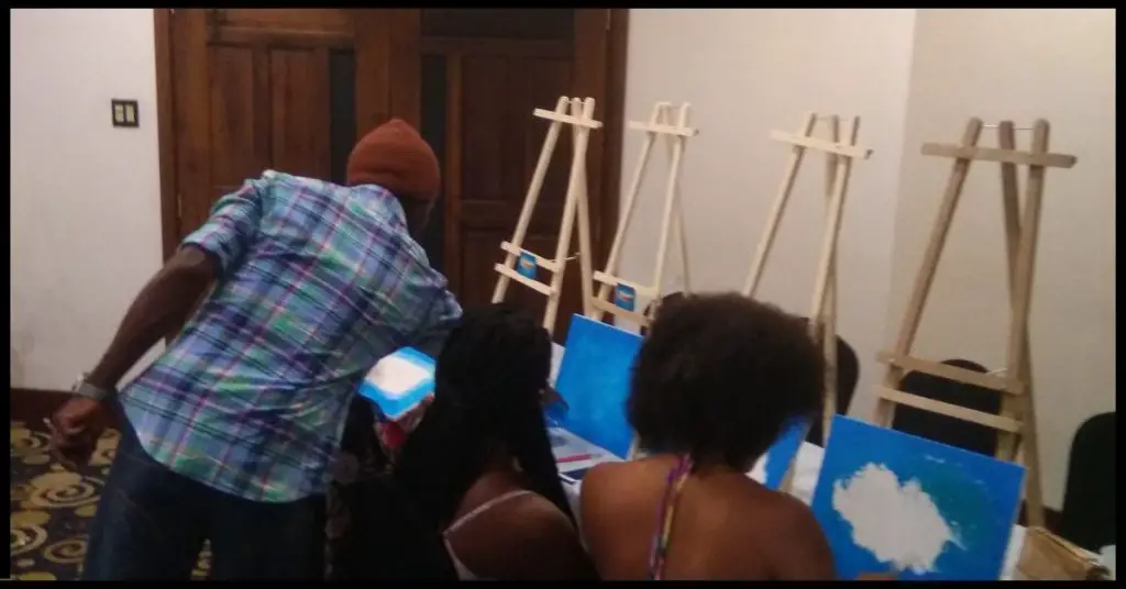 An Art Pro assisting participants at a sip and paint event