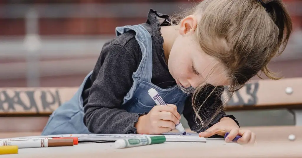 Little girl drawing with markers